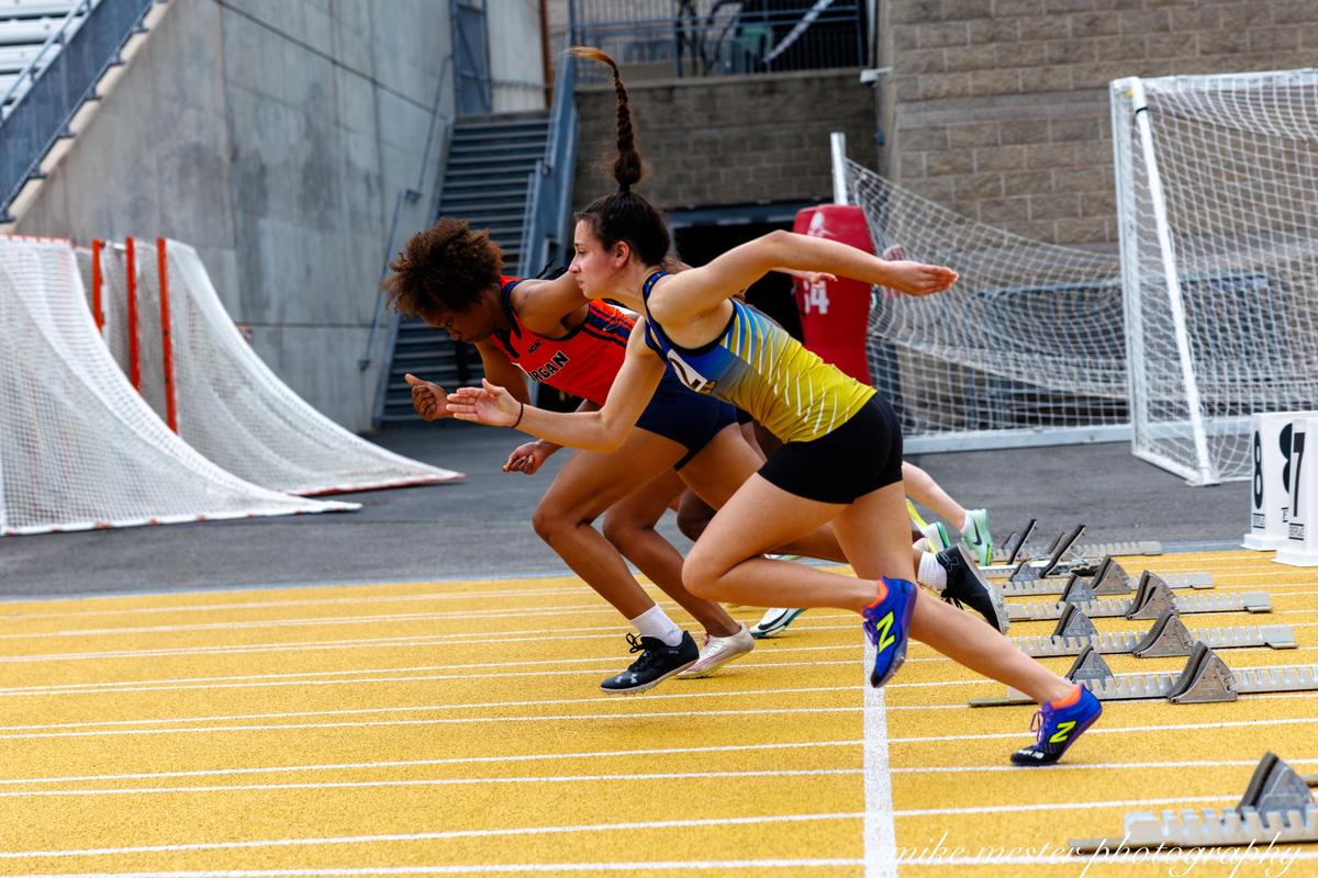 Track athletes launching from the starting line