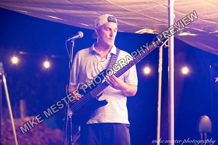 Bass guitarist performing beneath blue and amber stage lights.