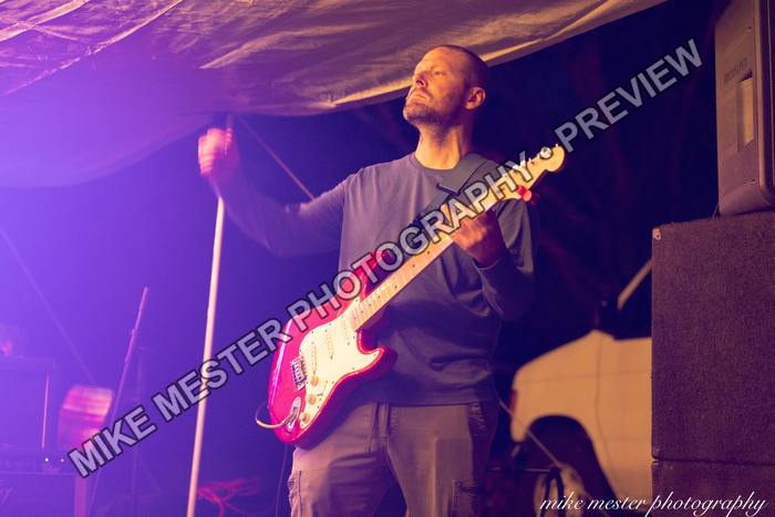 Guitarist raising one hand while holding a red electric guitar.