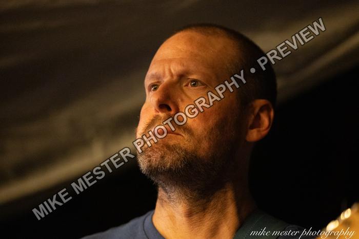 Close portrait of a guitarist lit by warm stage light.