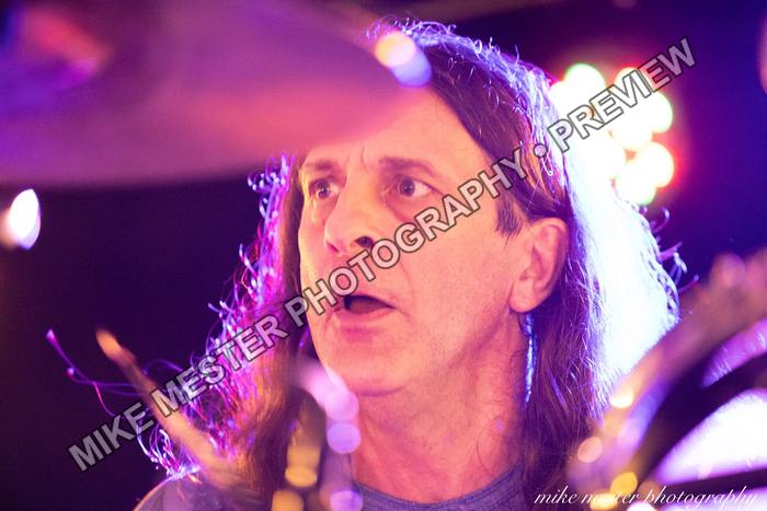 Drummer framed by cymbals and colorful stage lights.