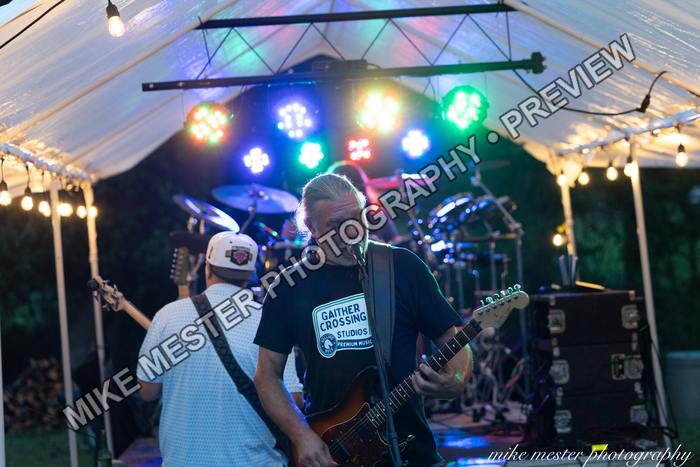Two guitarists performing together beneath the stage canopy.