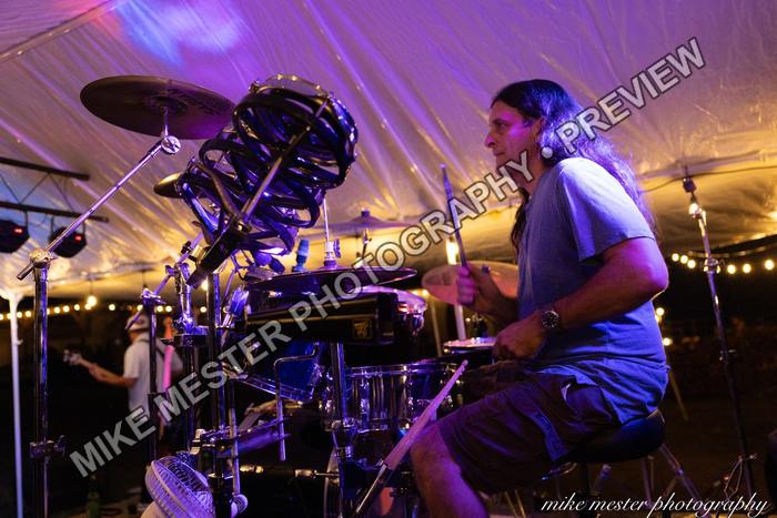 Side view of the drummer performing behind cymbals and drums.